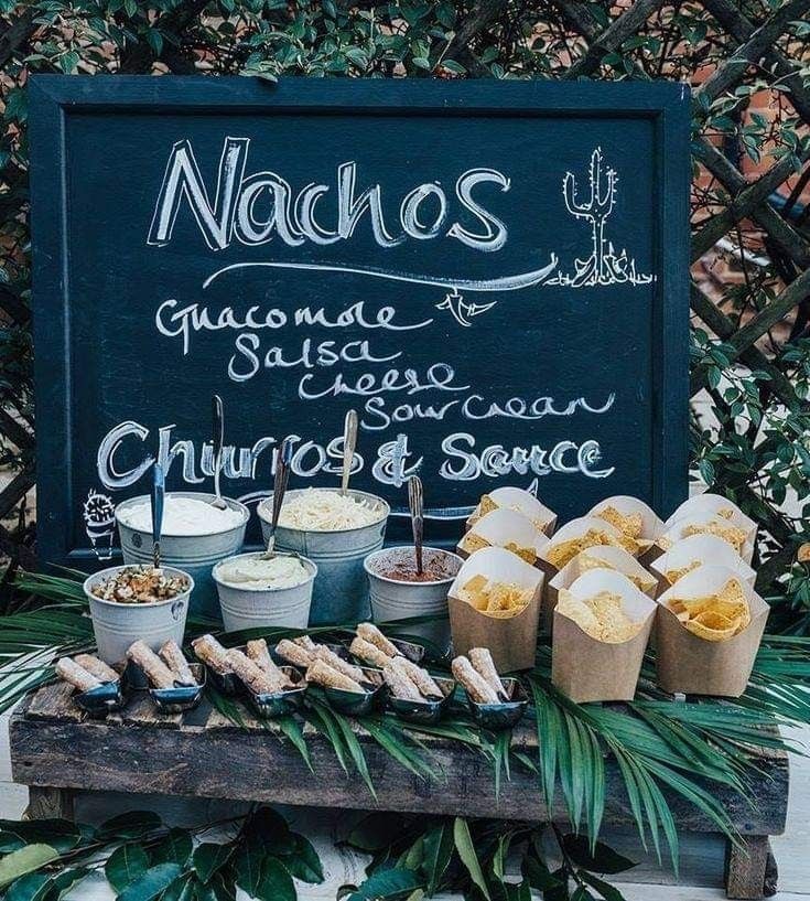 an assortment of food sitting on top of a table next to a chalkboard sign