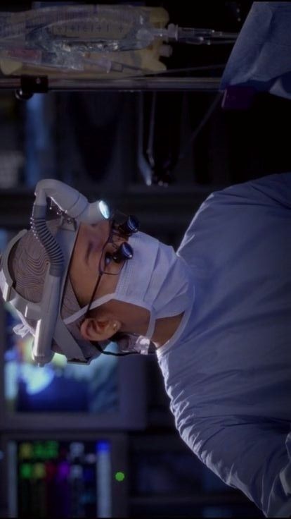 a man in white lab coat and safety goggles standing next to a monitor screen