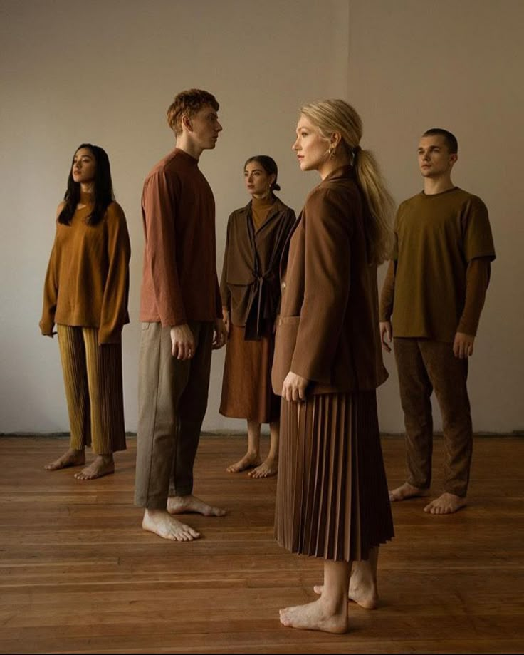 a group of people standing next to each other on a wooden floor in front of a white wall