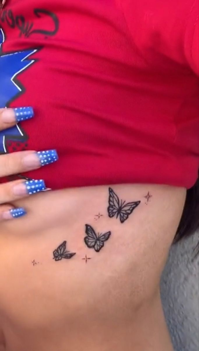 a woman's stomach with butterflies and stars on her belly, while she is wearing a red shirt