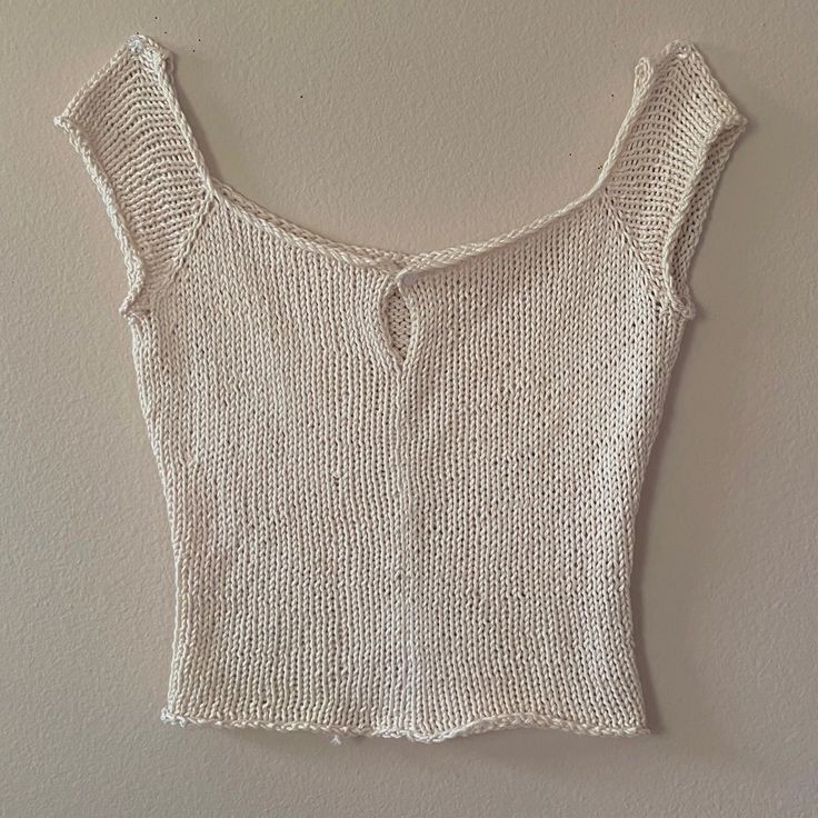 a white knitted top hanging on the wall