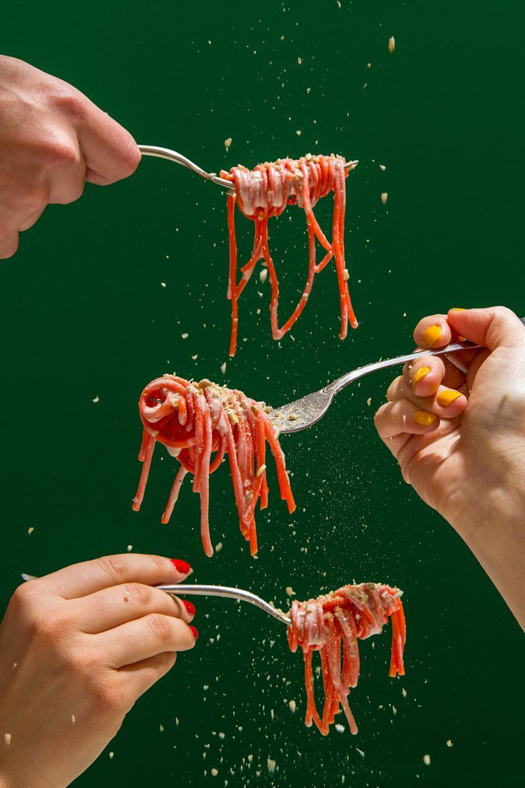 three people are eating spaghetti with red sauce on them and sprinkled with parmesan cheese