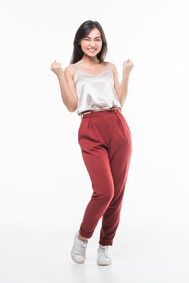 a woman in red pants and white top posing for the camera with her fist up