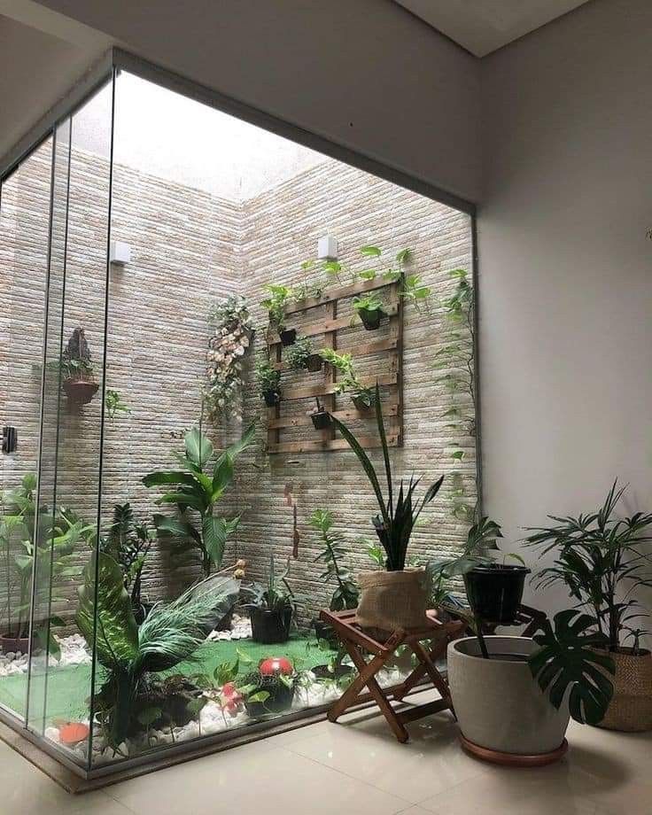 a room filled with lots of plants next to a wall mounted planter on a brick wall