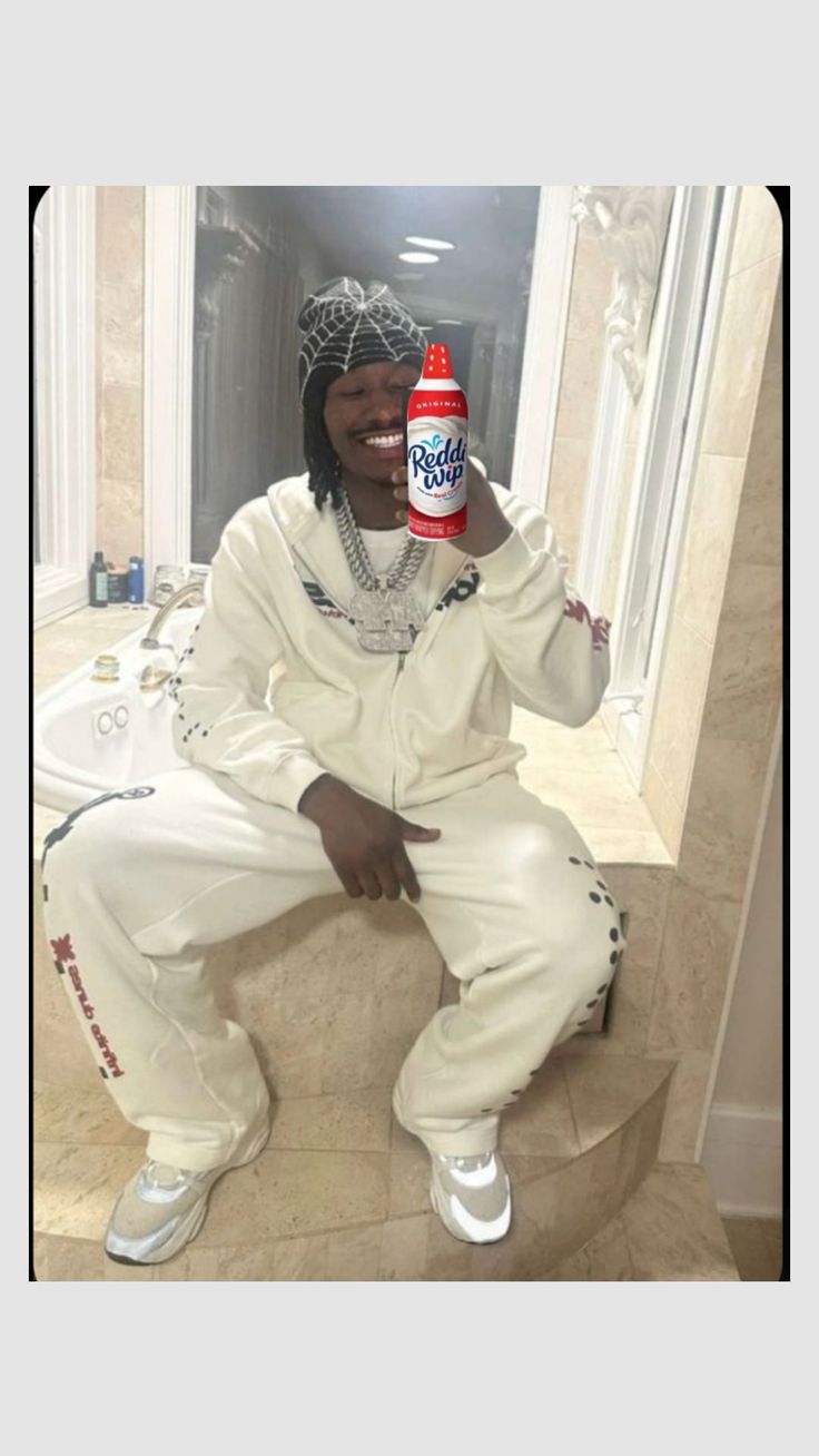 a man sitting on top of a step next to a bathroom sink holding a soda bottle