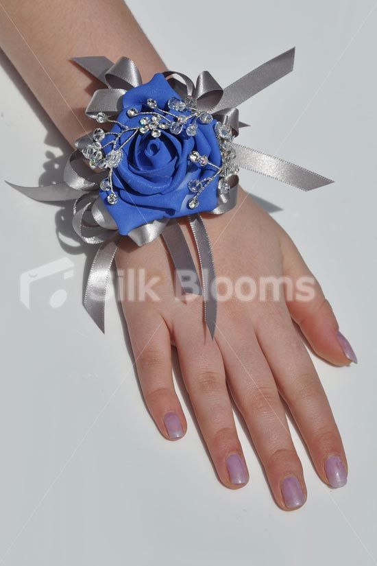 a woman's hand wearing a blue rose and silver ribbon bracelet with crystal accents