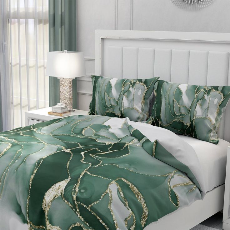 a bed with green and white comforter in a bedroom next to a lamp on a nightstand