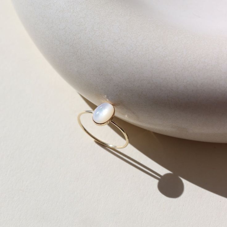 mother of pearl stone set in a bezel on a 14k gold fill skinny ring band Timeless Adjustable Oval Rings, Hypoallergenic Oval 14k Gold Jewelry, Dainty Oval Cabochon Birthstone Jewelry, Adjustable Gold Moonstone Cabochon Ring, 14k Gold Oval Cabochon Moonstone Ring, Delicate Oval Sterling Silver Rings, Dainty Oval Cabochon Gemstone Rings, Dainty Oval Cabochon Ring, Minimalist Oval Cabochon Wedding Jewelry