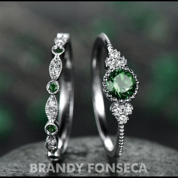 two wedding rings with green and white stones