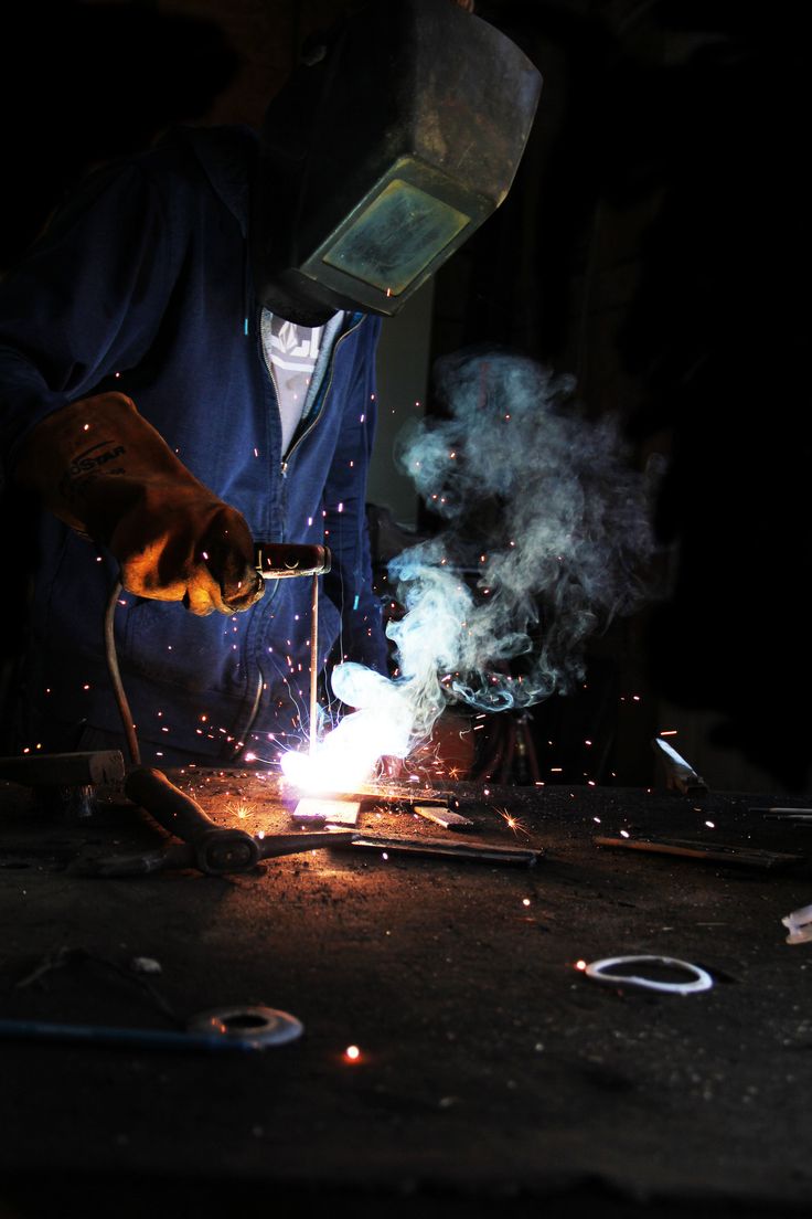 welder working on an object in the dark with sparks coming out of its hands