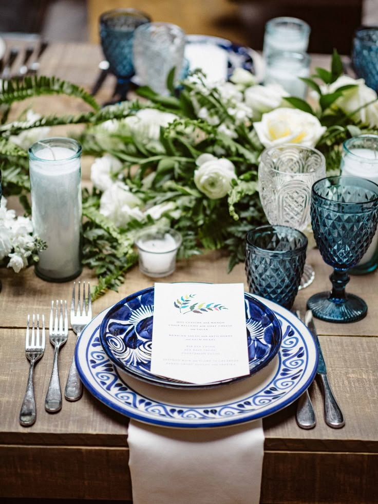 the table is set with blue and white plates, silverware, and napkins