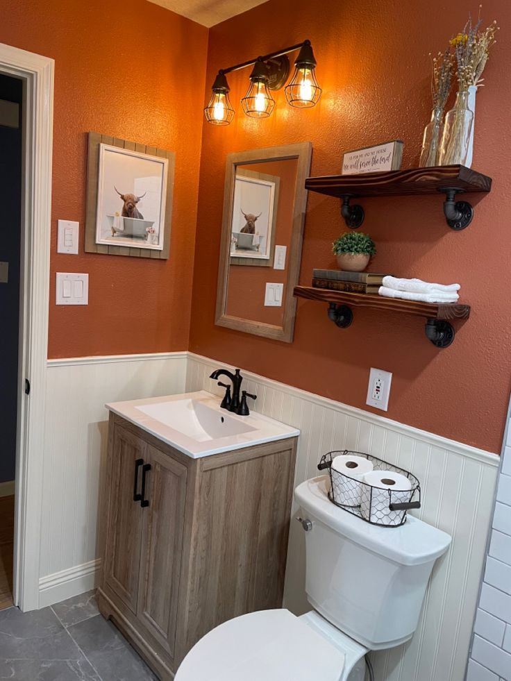 a bathroom with a toilet, sink and shelves on the wall next to each other