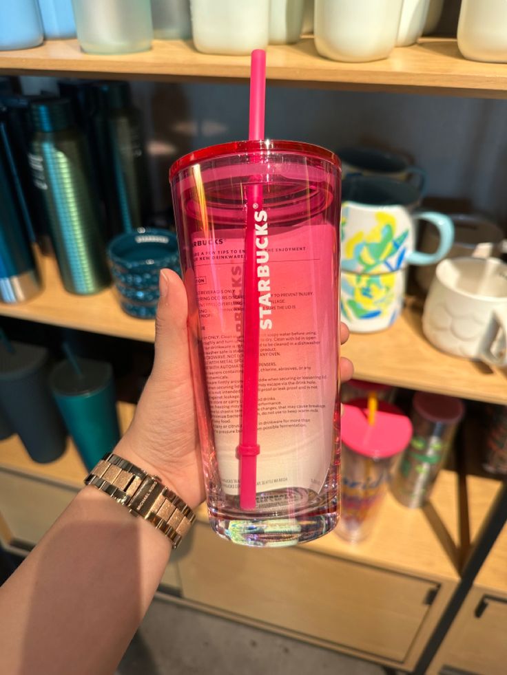 a person holding up a pink cup with a straw in it