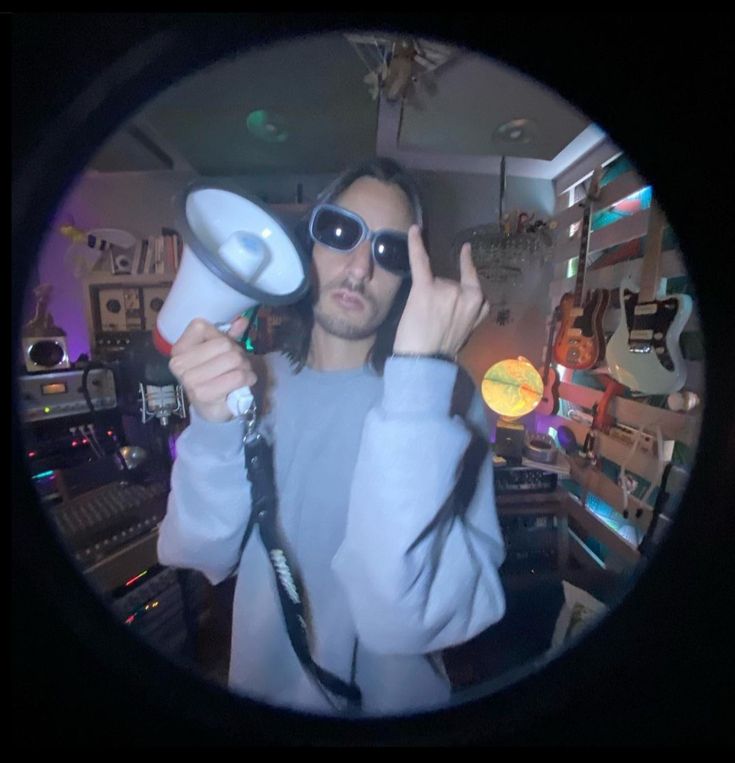 a man with sunglasses holding two hair dryers in front of his face and looking through the lens