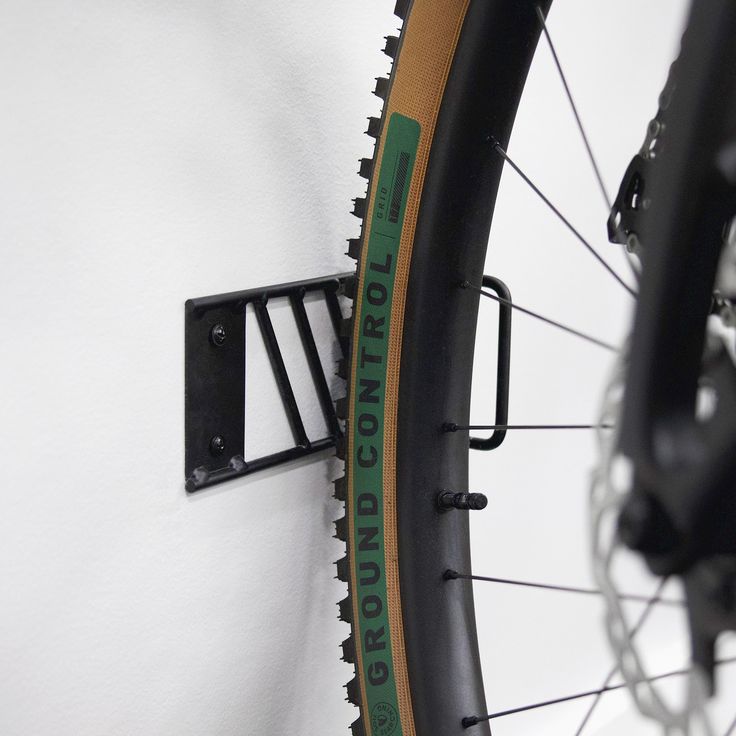 a bicycle tire mounted to the side of a white wall with green lettering on it