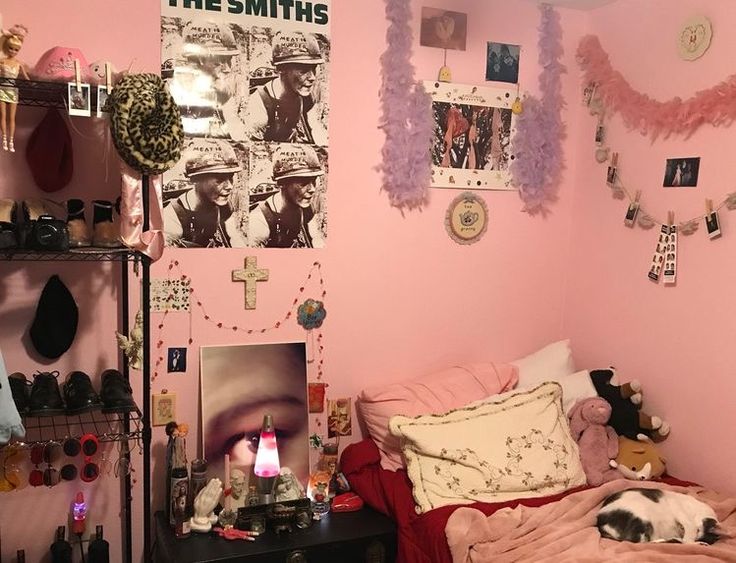 a small bedroom with pink walls and pictures on the wall, bedding and decorations