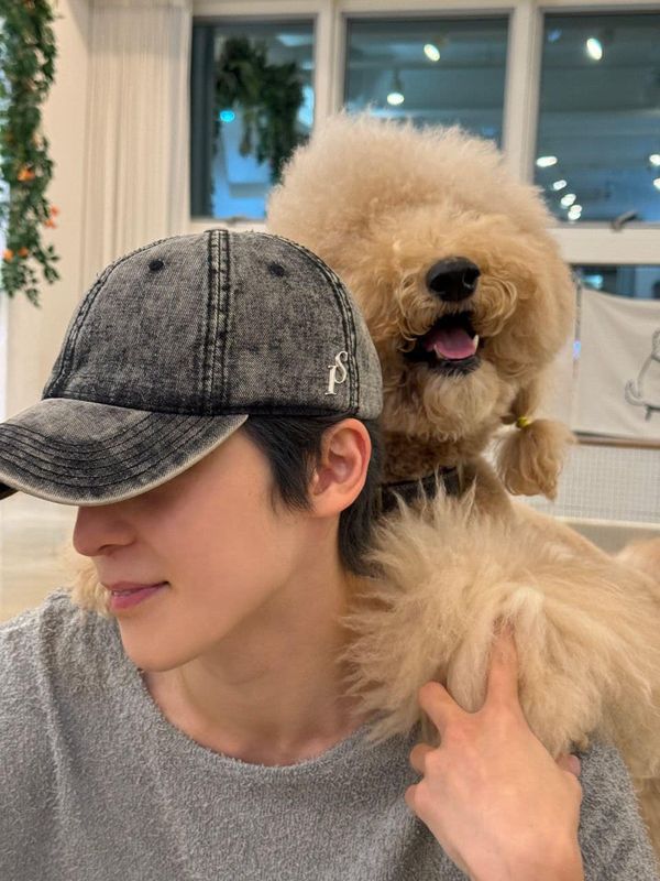 a man holding a dog on his shoulder and wearing a hat with it's ears up