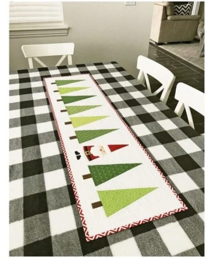 the table runner is decorated with green and red christmas trees on black and white checkered fabric