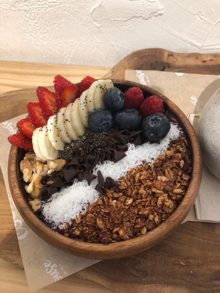 a wooden bowl filled with granola and fruit