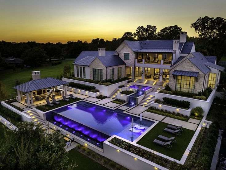 an aerial view of a house with a swimming pool in the foreground at sunset