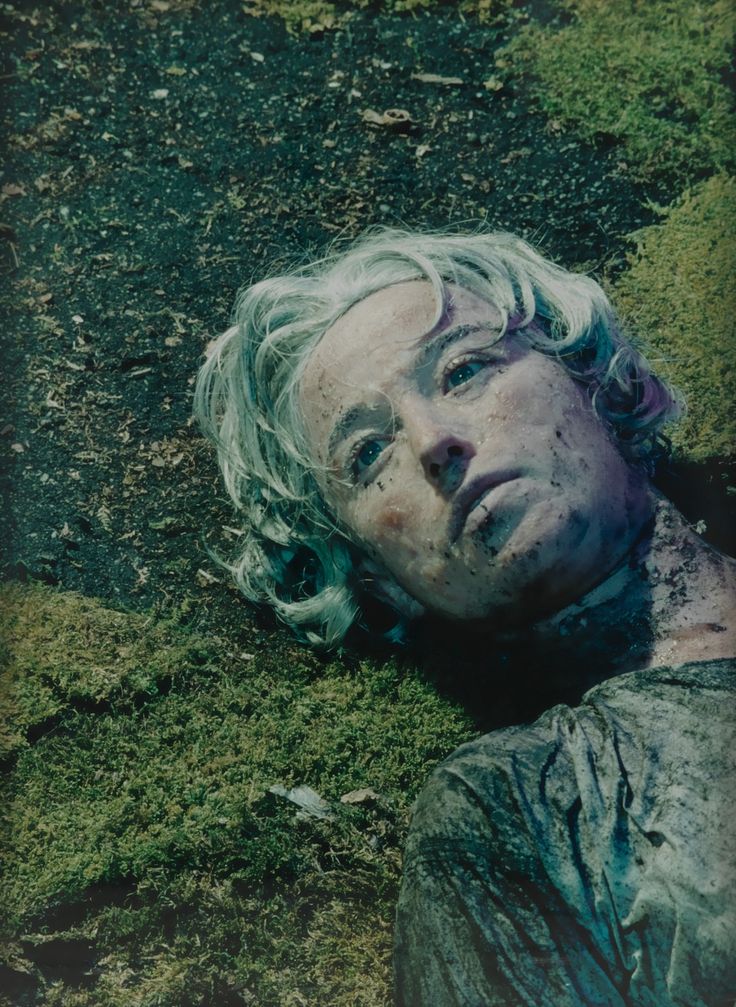 a man with white hair laying on the ground