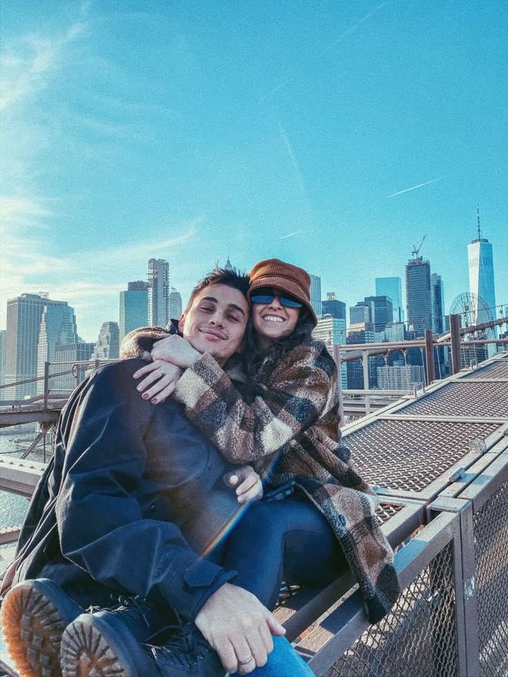 a man and woman sitting on top of a bridge