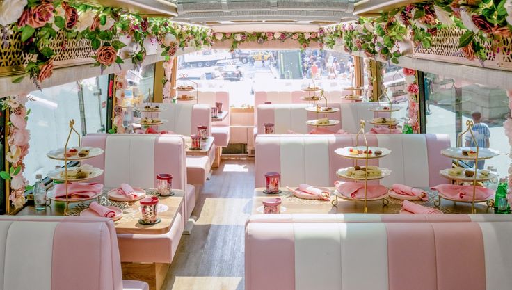 the interior of a fancy restaurant with pink and white booths, floral decorations, and flowers on the ceiling