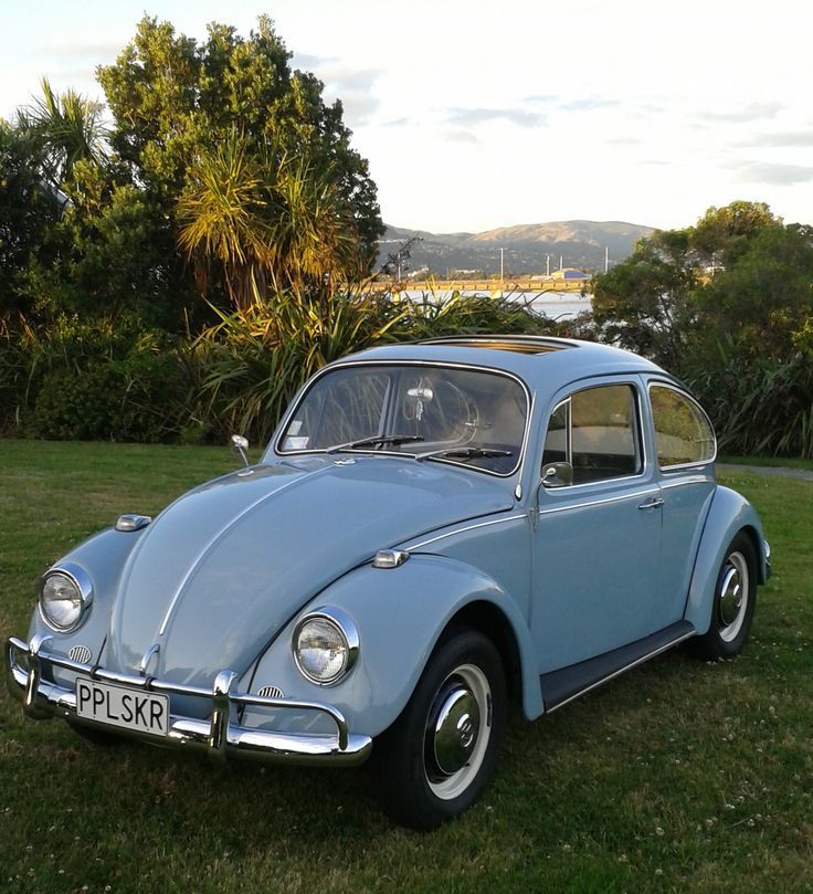 an old blue car is parked in the grass