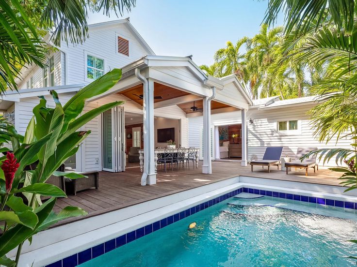 a house with a pool in front of it and palm trees around the back yard