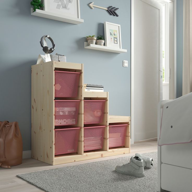 a child's bedroom with blue walls and pink baskets on the floor next to a bed