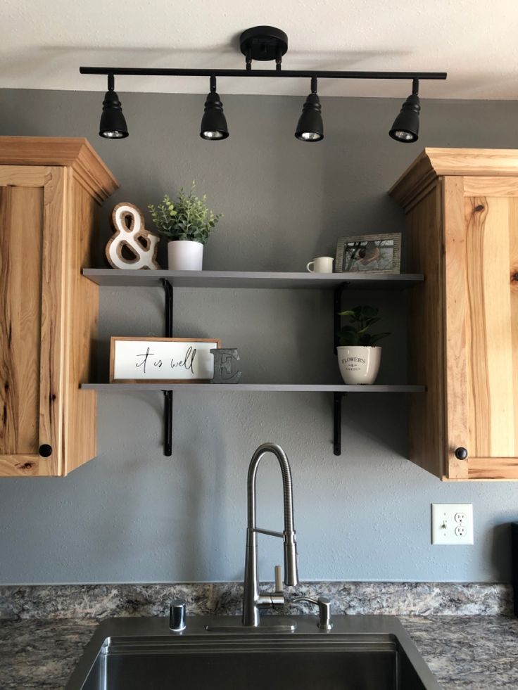 a kitchen sink under two black lights and some wooden cupboards with books on them