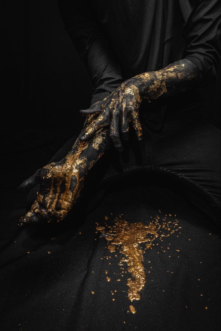 a person with black and gold paint on their hands