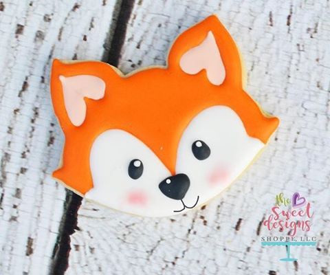 a close up of a cookie on a wooden surface with the face of a fox