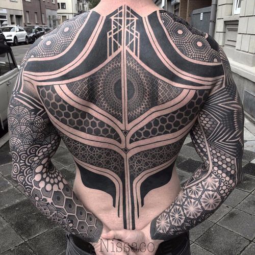 the back of a man's body with intricate designs on his upper and lower half