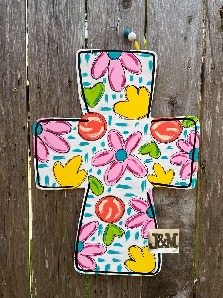 a decorative cross hanging on a wooden fence