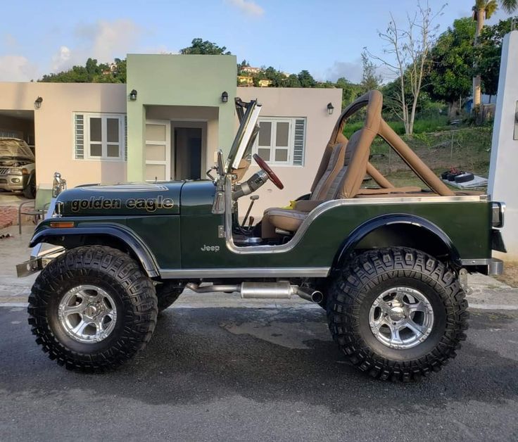 a green jeep parked in front of a house