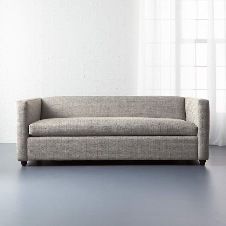 a gray couch sitting in front of a window