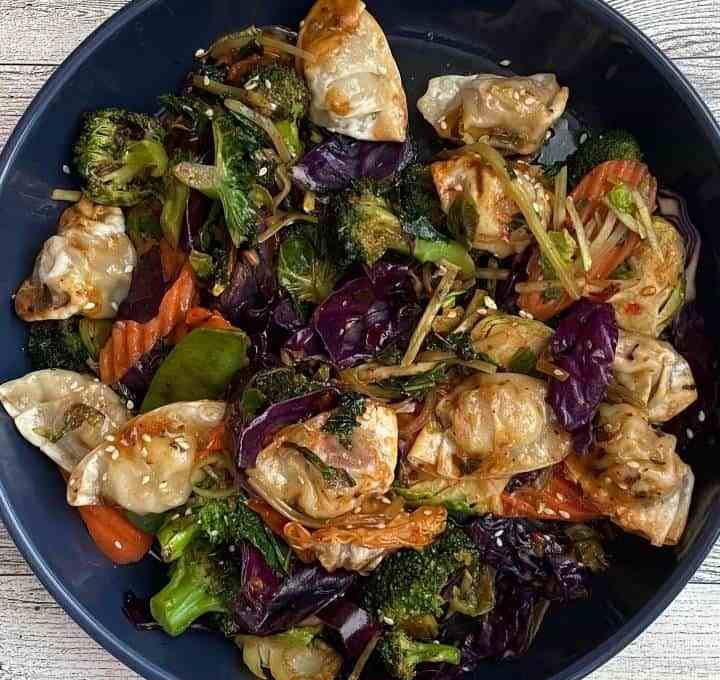 a blue bowl filled with vegetables on top of a wooden table