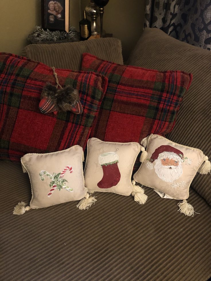 three christmas pillows on a bed with santa clause stocking and stockings hanging from the pillow