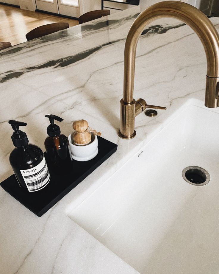 a bathroom sink with soap and lotion on it next to a faucet