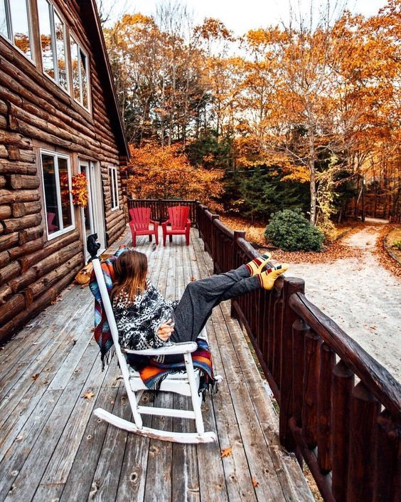 a woman sitting in a rocking chair on top of a wooden deck next to a building