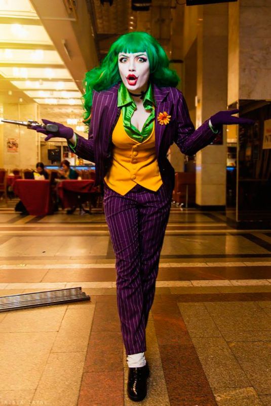 a woman dressed as the joker is walking through an airport lobby with her arms out