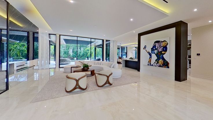 a large living room with white couches and art work on the wall behind it