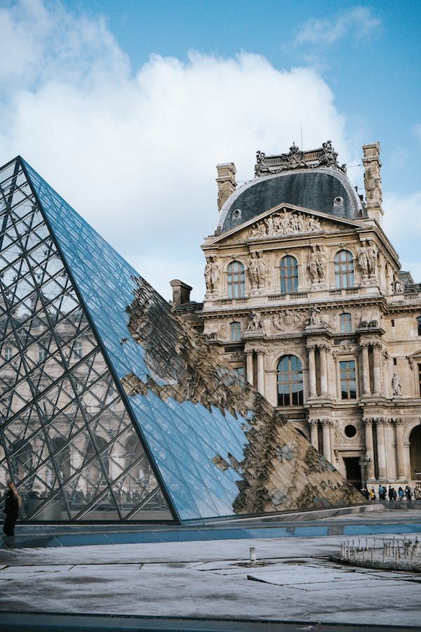 a large building with a glass pyramid in front of it