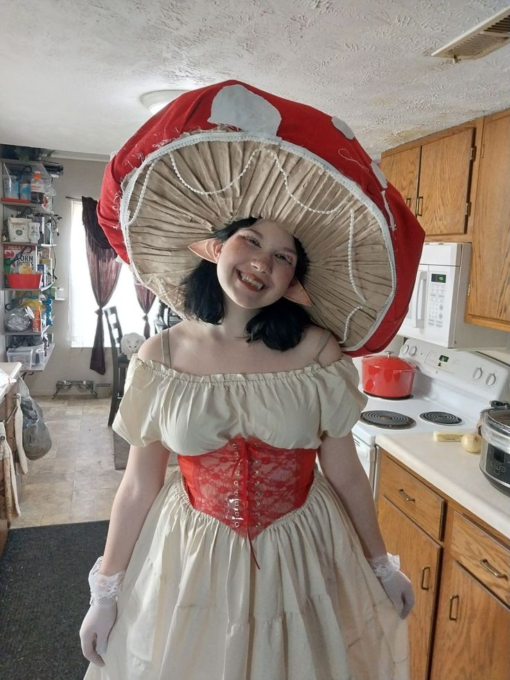 a woman in a dress and hat standing in a kitchen