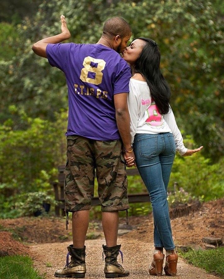 a man and woman kissing while standing on a path