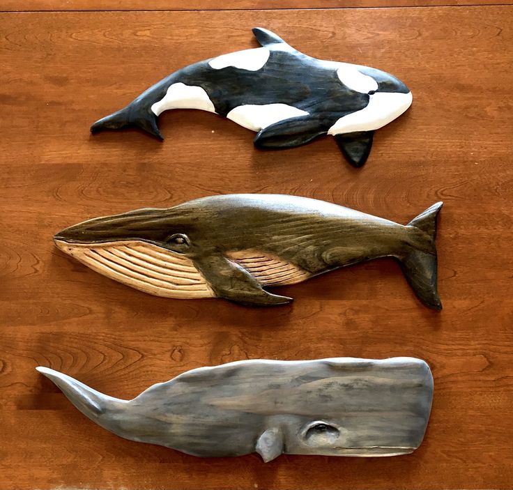 three metal whale sculptures sitting on top of a wooden table