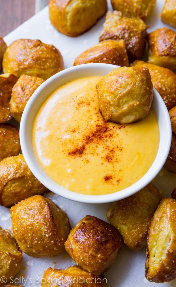 a white plate topped with rolls covered in cheese and dipping sauce next to some bread