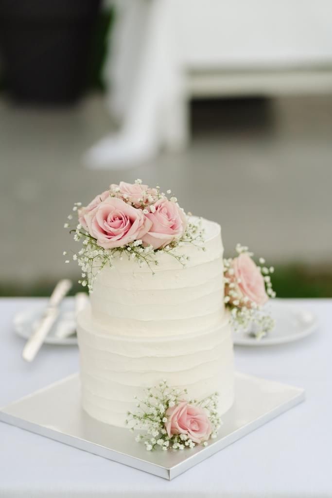 a white wedding cake with pink roses on top