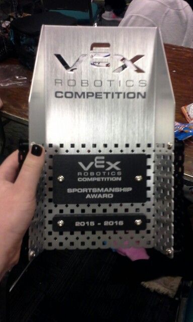 a person holding up a silver box with the words vx robotics competition written on it